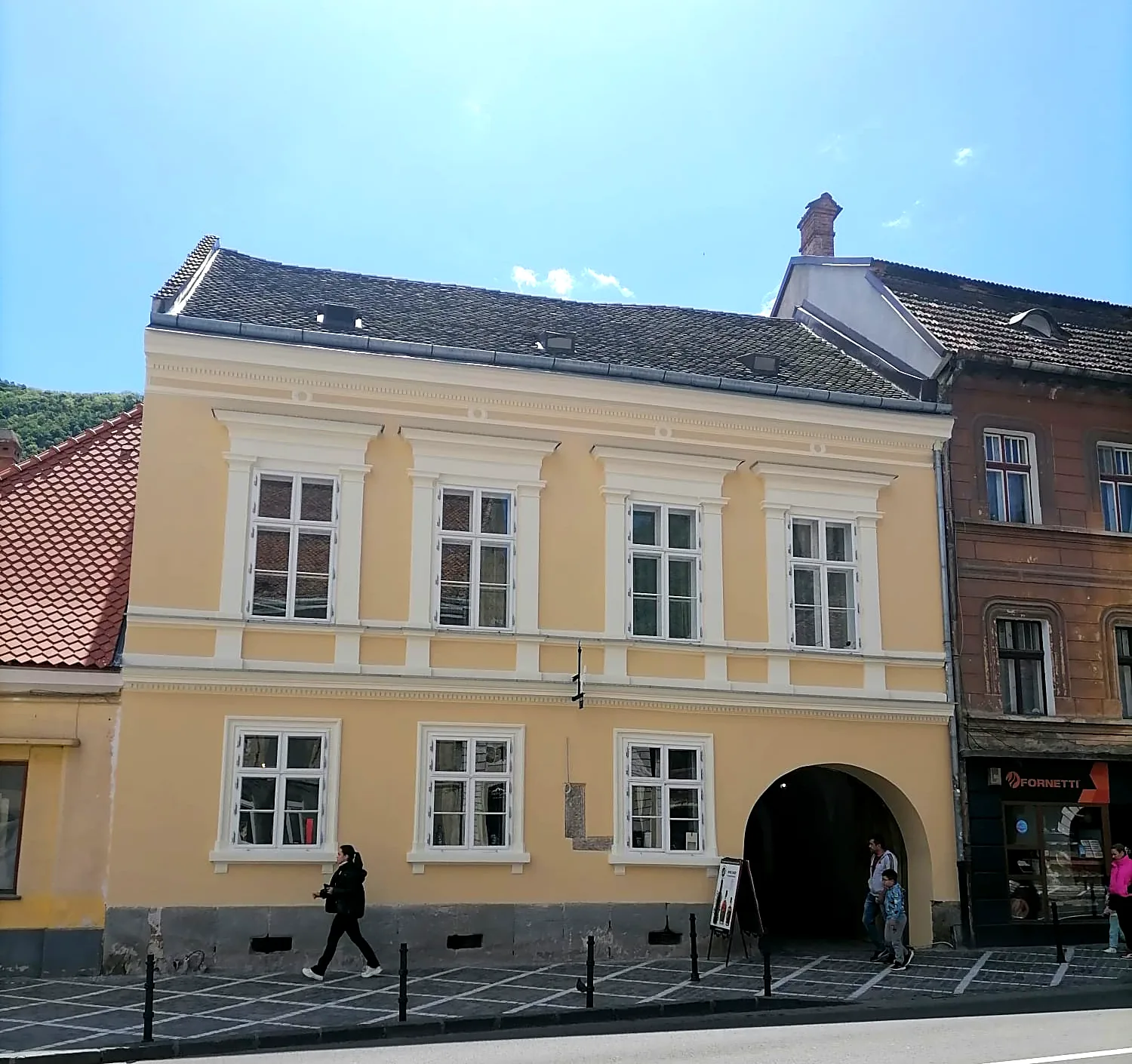 Die Fassade des Trausch-Hauses, George-Barițiu-Gasse 7, mit der gewölbten Toreinfahrt; dahinter der Turm der Schwarzen Kirche