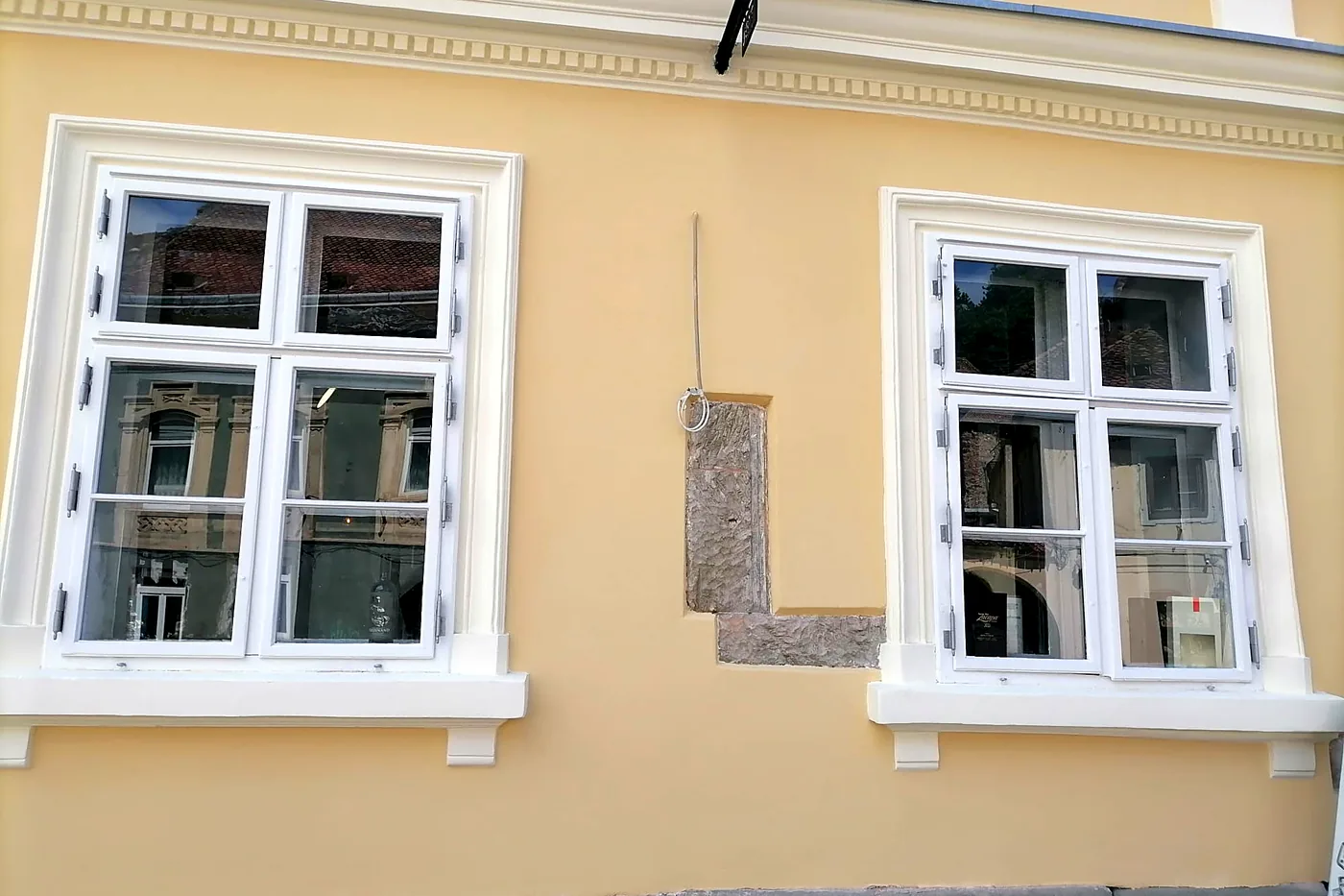 Zwei Erdgeschossfenster und ein im Putz freigelassenes Stück altes Steinmauerwerk