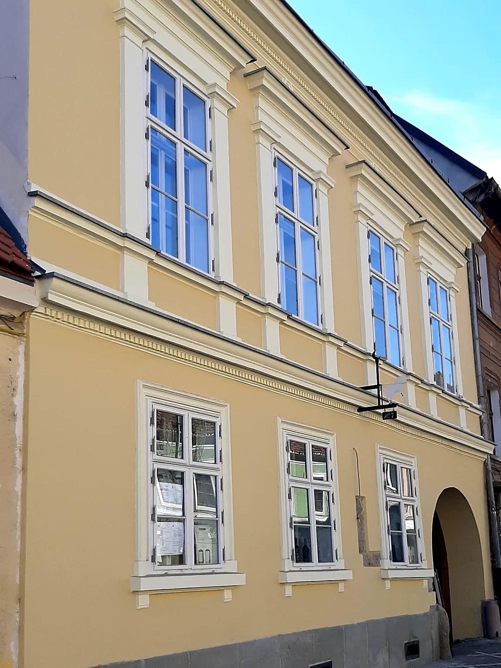 Die Fassade des Hauses in perspektivischer Ansicht, den Gehsteig entlang zur Toreinfahrt